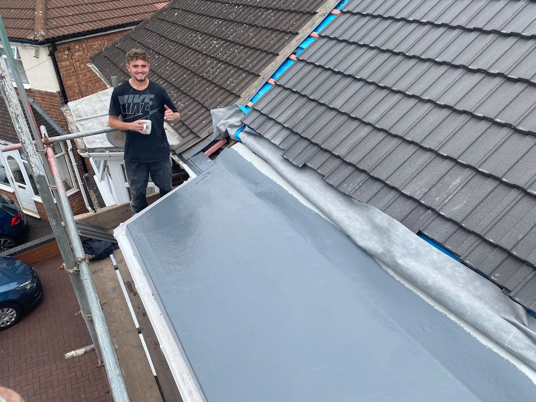 Roofing team member beside a newly waterproofed flat-roof area.