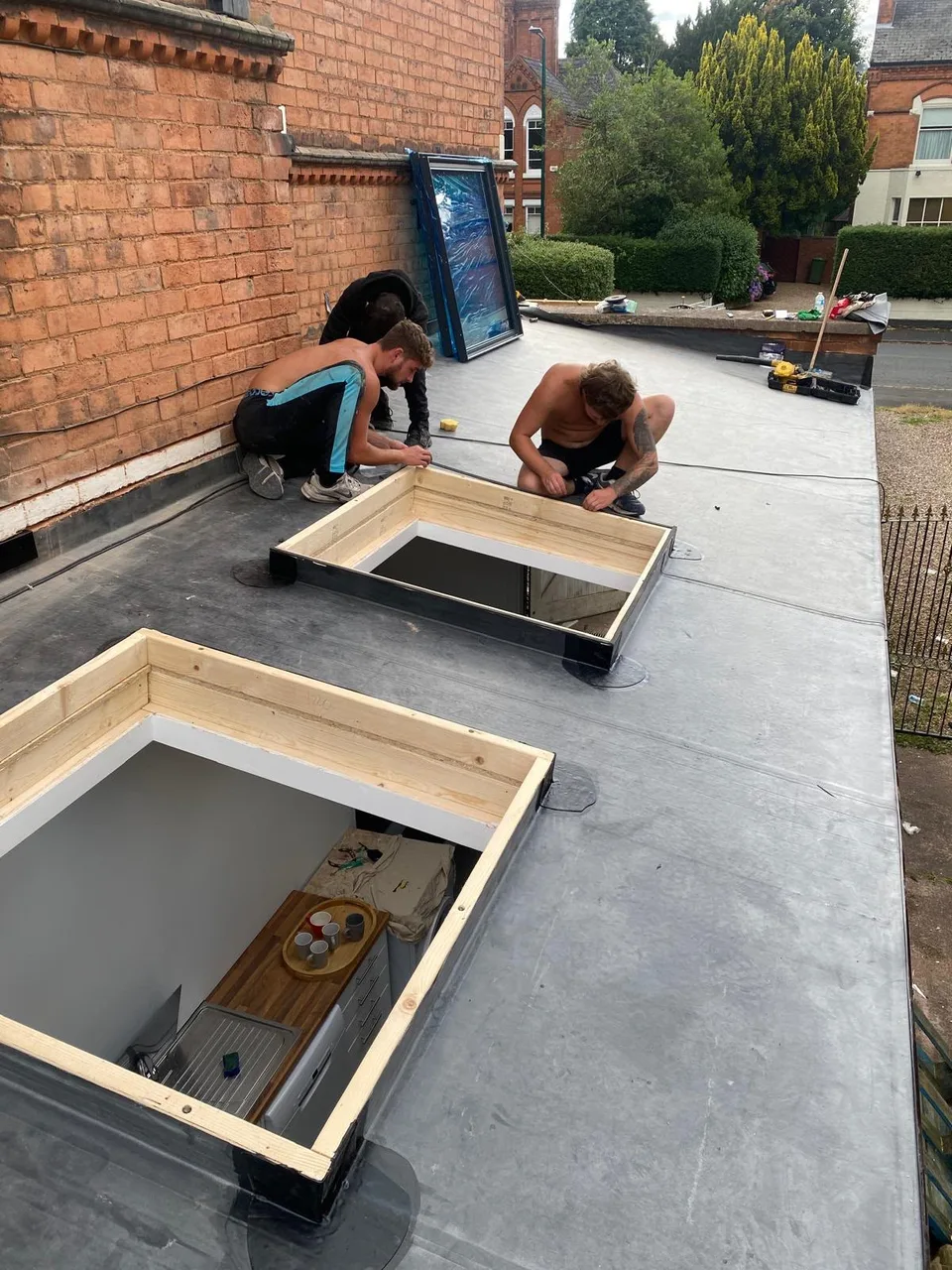 Team working around timber-framed rooflight openings, work in progress